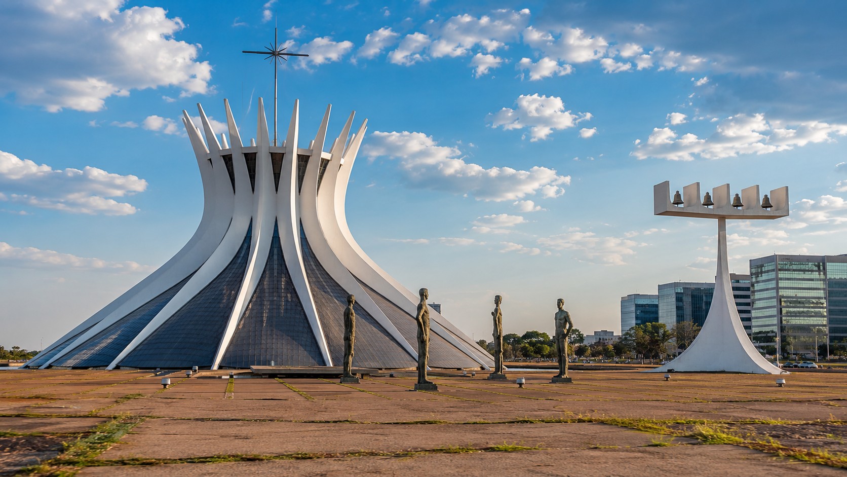 Photo professionnelle ultra réaliste en format 16/9 de la cathédrale métropolitaine de Brasília sous un ciel ensoleillé, avec architecture moderne en béton blanc, statues au premier plan, bâtiments urbains en arrière-plan et lumière naturelle douce.