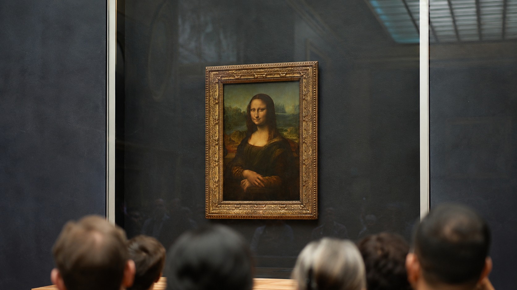 Photo professionnelle ultra réaliste de la Joconde exposée dans un musée type Louvre, avec visiteurs flous au premier plan, cadre doré, mur sombre, lumière naturelle douce, format 16/9, 25-06-2026