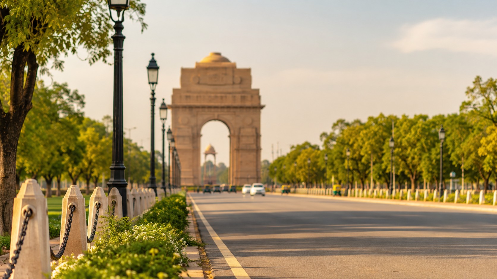 New Delhi capitale de l’Inde avec avenue arborée ensoleillée menant vers India Gate, circulation légère, lampadaires noirs, végétation verte, photo professionnelle réaliste 2026 format 16/9