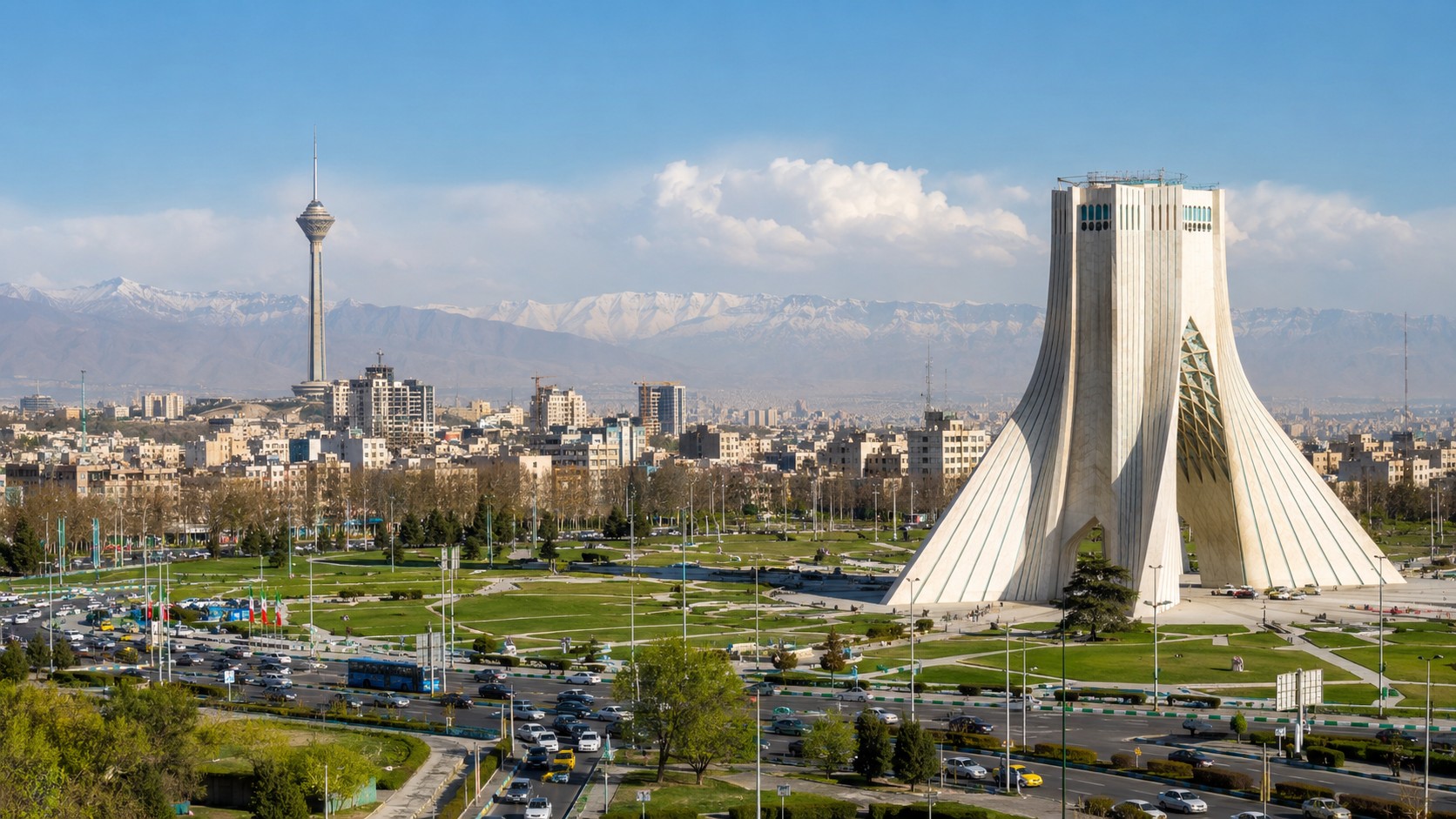 Vue panoramique ensoleillée de Téhéran, capitale de l’Iran, avec la tour Azadi au premier plan, la tour Milad, les avenues urbaines, les espaces verts et les montagnes de l’Alborz en arrière-plan, image professionnelle réaliste du 2026-07-15 au format 16:9.